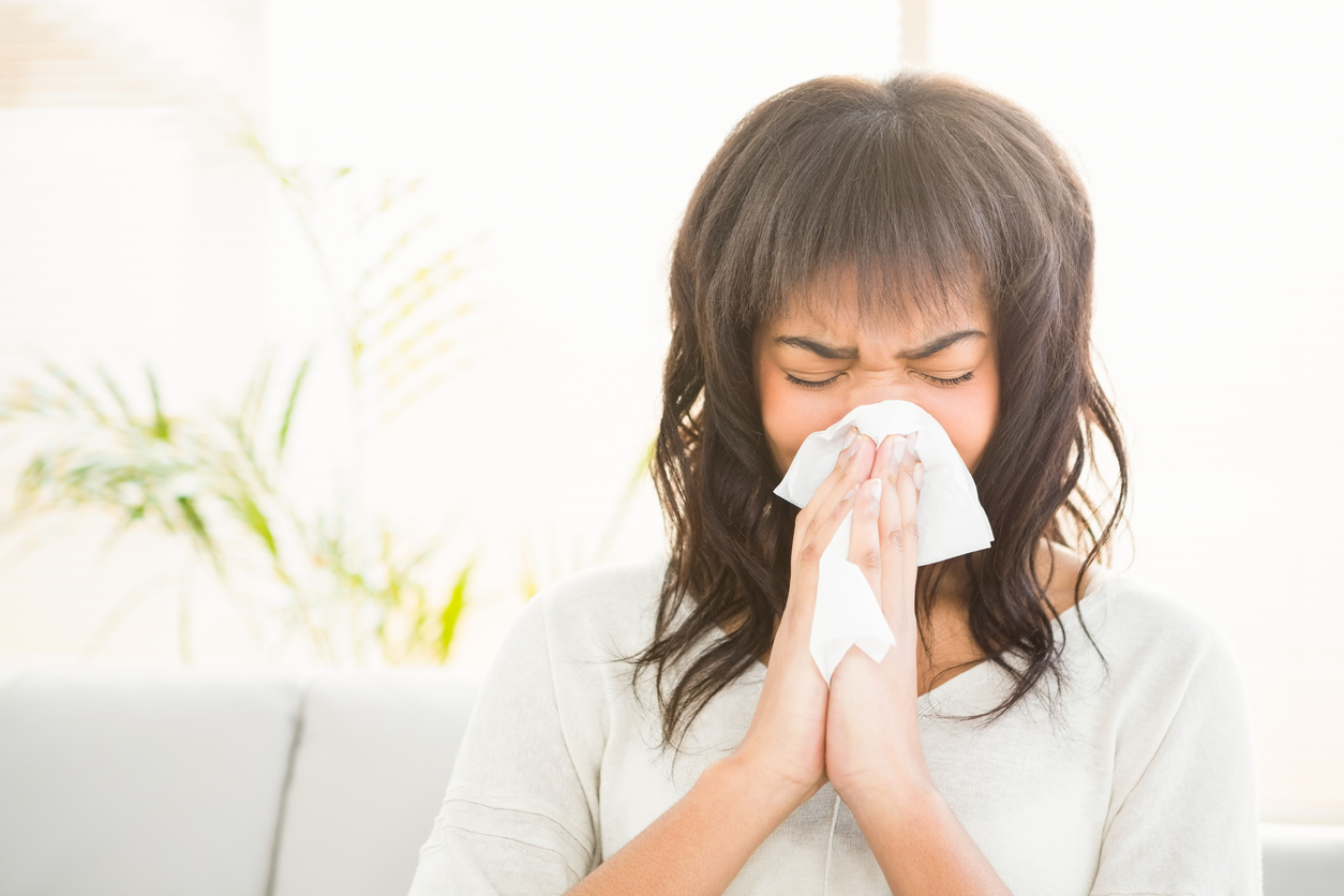 A woman covering her nose with a tissue as she sneezes