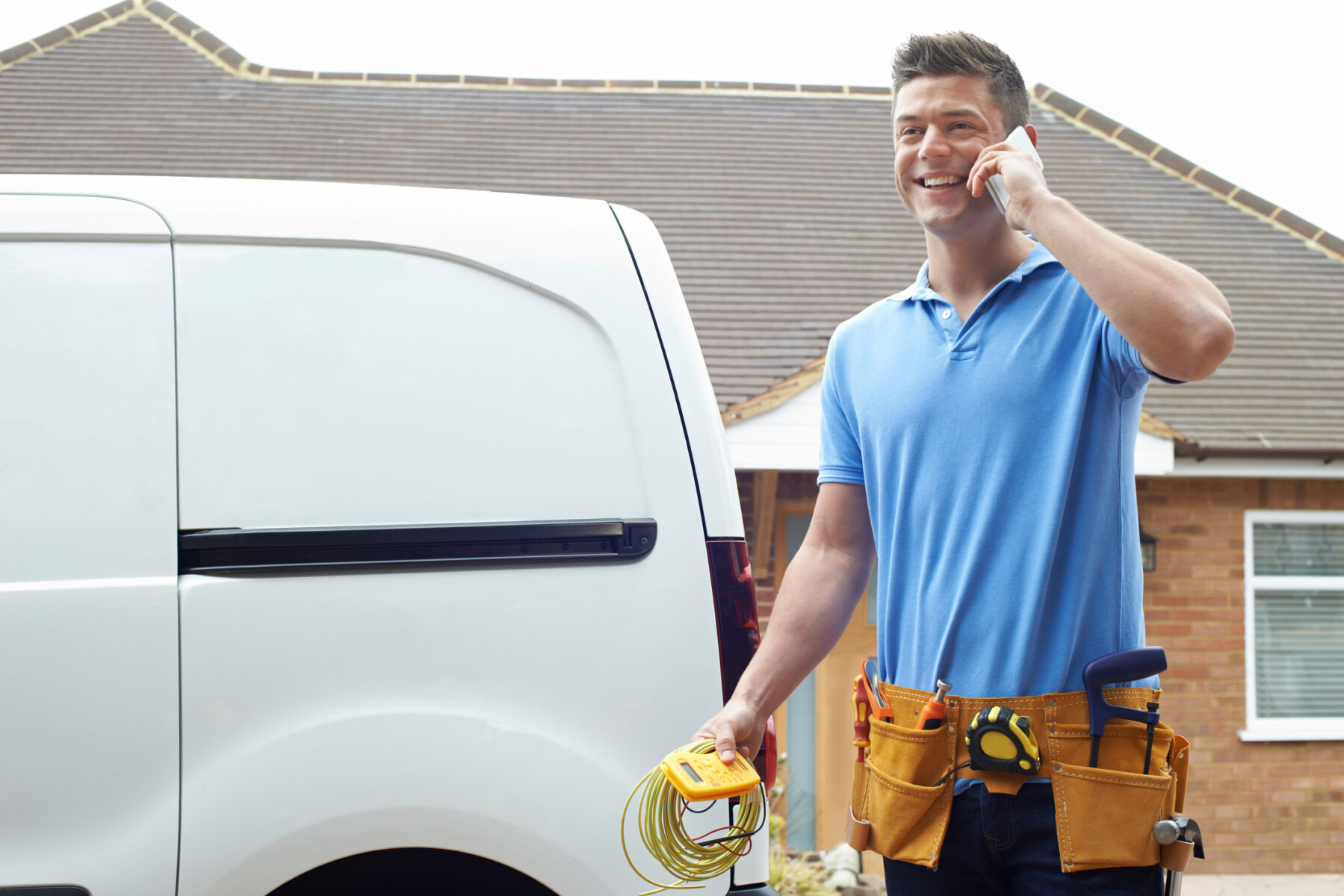 HVAC technician on the phone next to a white work truck in a residential area