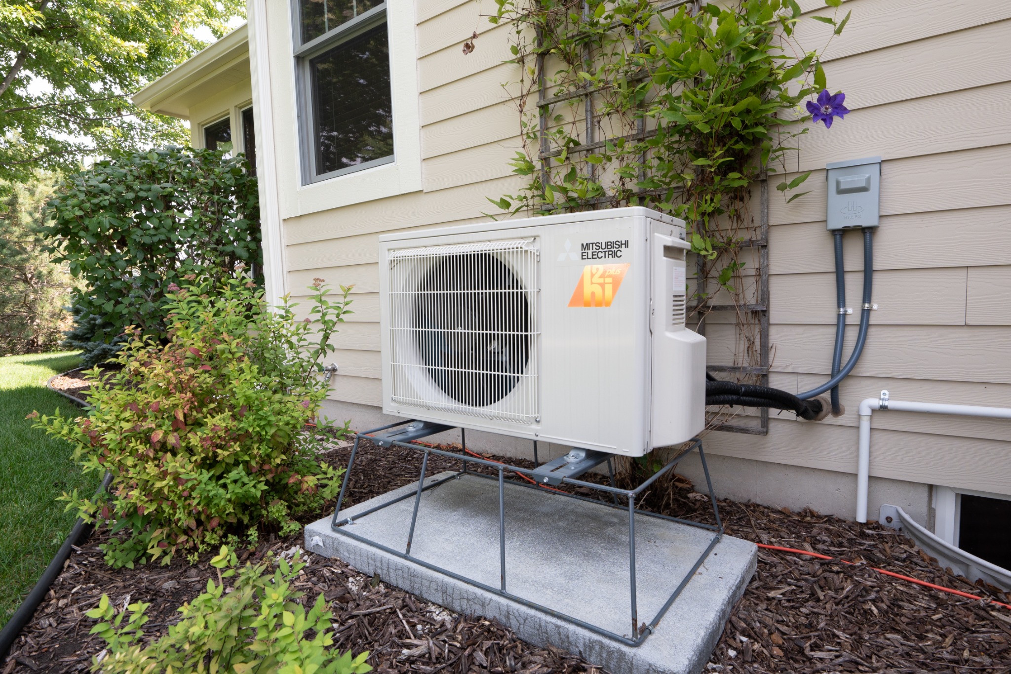 Mitsubishi Ductless Mini-Splits in Southeastern Wisconsin 3 Mitsubishi Electric outdoor heat pump mounted on an elevated stand beside a home
